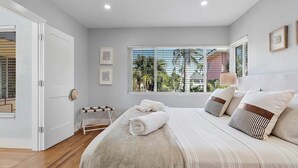 A bedroom with a large bed, a window with blinds, a bedside table, and a door. - Modern 1-bedroom apartment, Walk to Las Olas Blvd and Beach, Free parking (Fort Lauderdale)