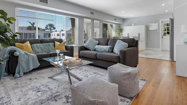 A modern living room with a grey sofa, a glass coffee table, and a patterned rug. - Modern 1-bedroom apartment, Walk to Las Olas Blvd and Beach, Free parking (Fort Lauderdale)