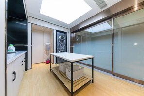 A compact laundry room with a washing machine, a drying rack, and a table. - JI Hotel (Jiaxing Zhongshan Road) (Jiaxing)