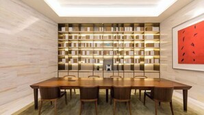 A modern dining area with a long wooden table and chairs, a built-in bookshelf, and a framed artwork on the wall. - JI Hotel (Jiaxing Zhongshan Road) (Jiaxing)