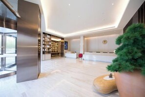 A modern hotel lobby with a reception desk, a seating area, and a large potted plant. - JI Hotel (Jiaxing Zhongshan Road) (Jiaxing)