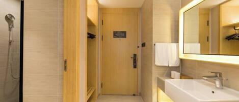 Un baño moderno con un espejo grande, un lavamanos y una ducha.