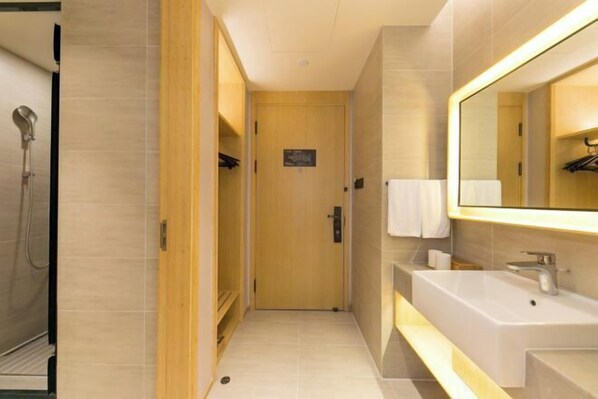 A modern bathroom with a large mirror, a sink, and a shower.