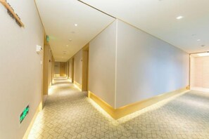 A hotel corridor with a geometric patterned floor, recessed lighting, and a plain wall on one side. - JI Hotel (Jiaxing Zhongshan Road) (Jiaxing)