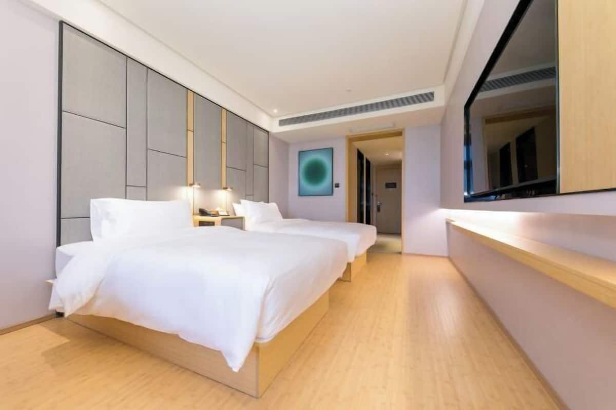 A hotel room with two beds, a large mirror, and a modern design.