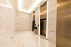 A modern interior with a polished marble floor, a potted plant, and a metallic elevator. - JI Hotel (Jiaxing Zhongshan Road) (Jiaxing)