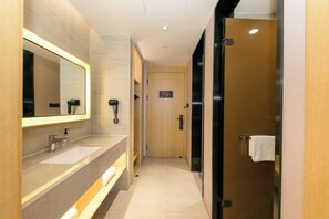 A modern bathroom with a large mirror, two sinks, a towel rack, and a door leading to another room.