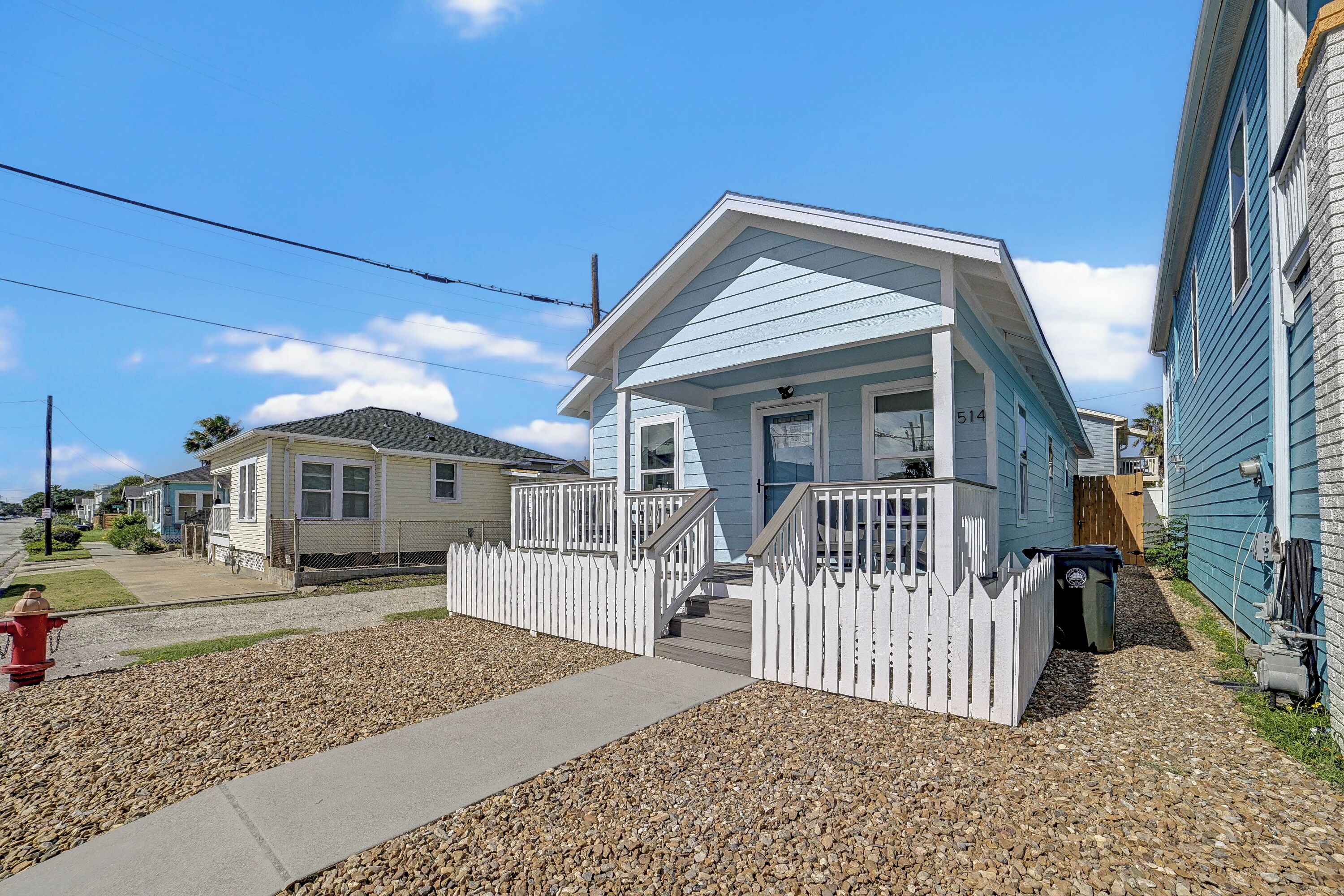 A residential property with a front porch, a small deck, and a white picket fence.