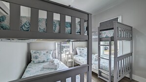 A bunk bed room with a window, a small table, and a chair. - Nautical Nest - 1 block to the Beach, Newly Renovated (Galveston)