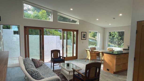 A spacious living room with a sofa, chairs, a coffee table, and a kitchen area with a dining table. - Charming 2-bedroom guest house in quiet neighborhood.  

 (Goleta)
