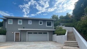 A modern two-story house with a garage, stone-paved driveway, and a concrete staircase leading to the garage. - Charming 2-bedroom guest house in quiet neighborhood.  

 (Goleta)