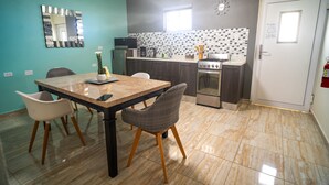 Une cuisine compacte comprenant un coin repas, un four à micro-ondes, une cuisinière et un évier.