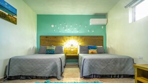 Une chambre avec deux lits, une tête de lit en bois, un mur de couleur turquoise et un plancher en bois.