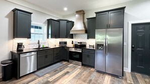 Una cocina moderna con armarios oscuros, electrodomésticos de acero inoxidable y piso de madera.