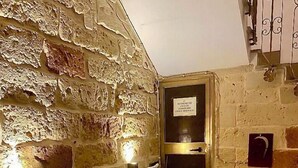 A stone-walled hallway with a wooden floor, a door with a sign, and a staircase with metal railings. - HABITARE Lecce & Salento (Lecce)