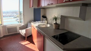 Una cocina con armarios rojos, un ventanal y vistas a un puerto deportivo.