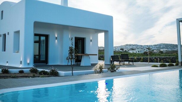 Ein modernes, weißes Gebäude mit Pool, Außenbereich und Blick auf die Landschaft.
