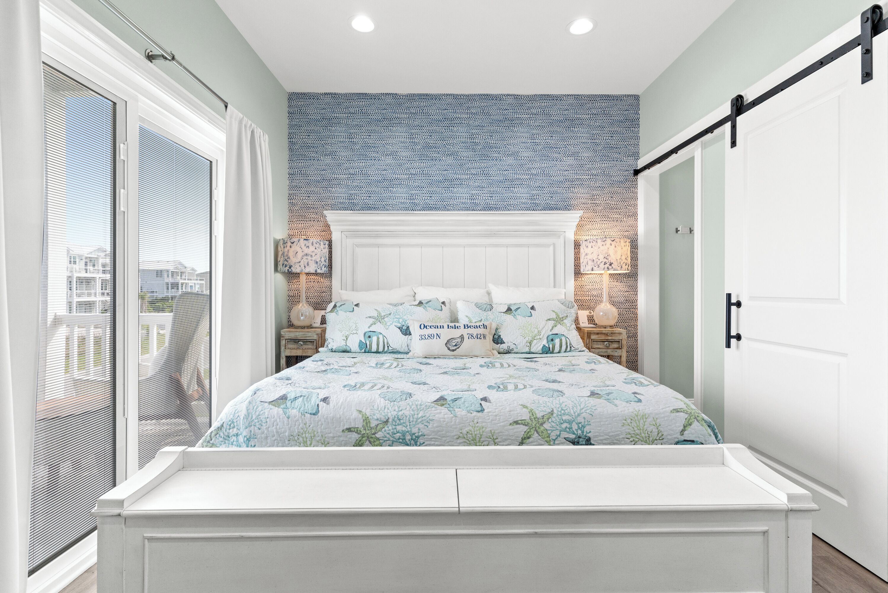 A bedroom with a bed, a sliding door, a nightstand, and a wall with a blue pattern.