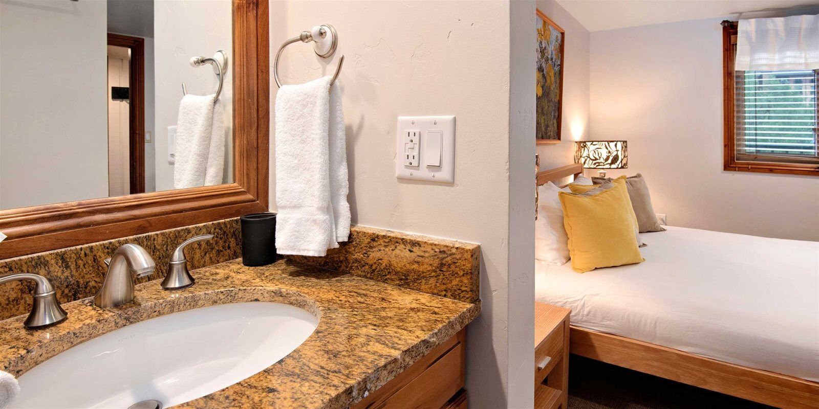 Une salle de bain avec un lavabo doté d’un plan de travail en granit, un miroir et un porte-serviettes.