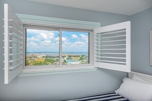 Une chambre avec une grande fenêtre, un lit et une vue sur un parc d’attractions situé au loin.