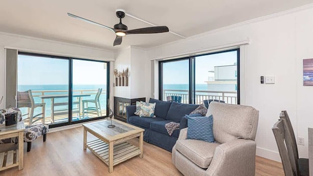 Ein geräumiges Wohnzimmer mit großem Fenster, Deckenventilator, Sofa, Couchtisch und Meerblick.
