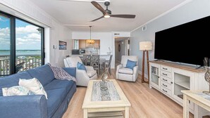 Ein Wohnzimmer mit Sofa, Couchtisch, TV-Möbel und Deckenventilator.