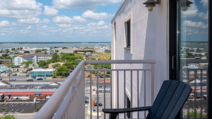 Ein Balkon mit Blick auf eine Küstenstadtlandschaft, darunter ein Riesenrad und Gebäude.