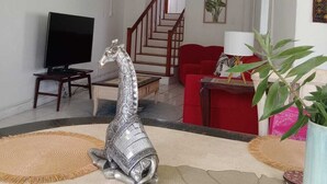 Una sala de estar con una televisión, una escultura decorativa de plata, una escalera y un sofá rojo.