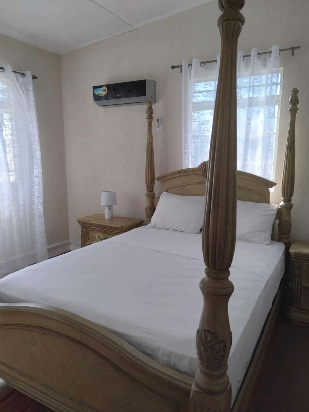 A four-poster bed with white linens in a room with a wooden headboard and nightstands.