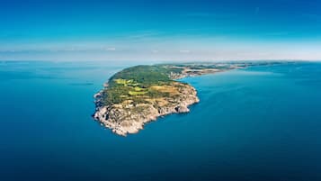 Vista aérea de una isla costera con un pequeño asentamiento, rodeada de un mar azul intenso.