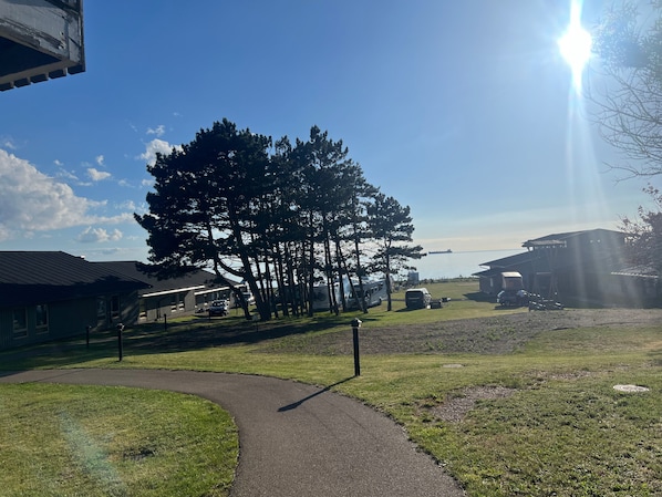 A campground with RVs parked on a grassy area, a paved path, and buildings with a simple, functional design.