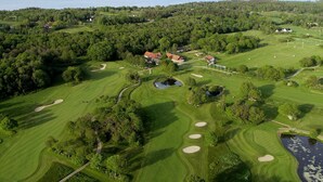 An aerial view of a golf course with multiple bunkers, a pond, and a large body of water in the background. - Visit Örestrand (Strandbaden)