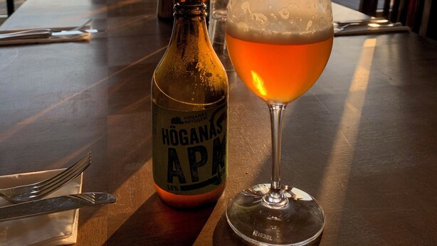 A table with a bottle of Höganas ABP beer, a glass of beer, and a candle holder. - Visit Örestrand (Strandbaden)