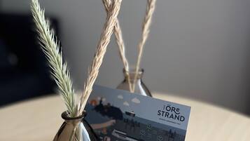 A glass vase with wheat stalks and a brochure titled "Löre Strand" on a wooden surface.