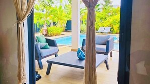 Une chambre avec vue sur une piscine et un espace salon extérieur.