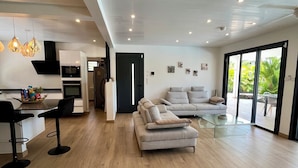 Un espace de vie moderne comprenant une cuisine, un coin repas et un espace détente avec un canapé et une table basse.