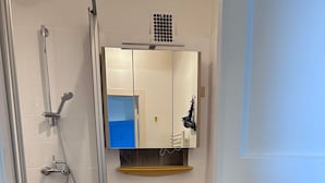 Kylpyhuone, jossa on keltainen pesuallas, wc-istuin, suihku ja peili.