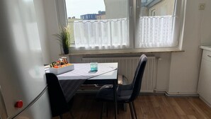 Pieni ruokailutila, jossa on pöytä, tuoleja ja ikkuna, jossa on verhot.