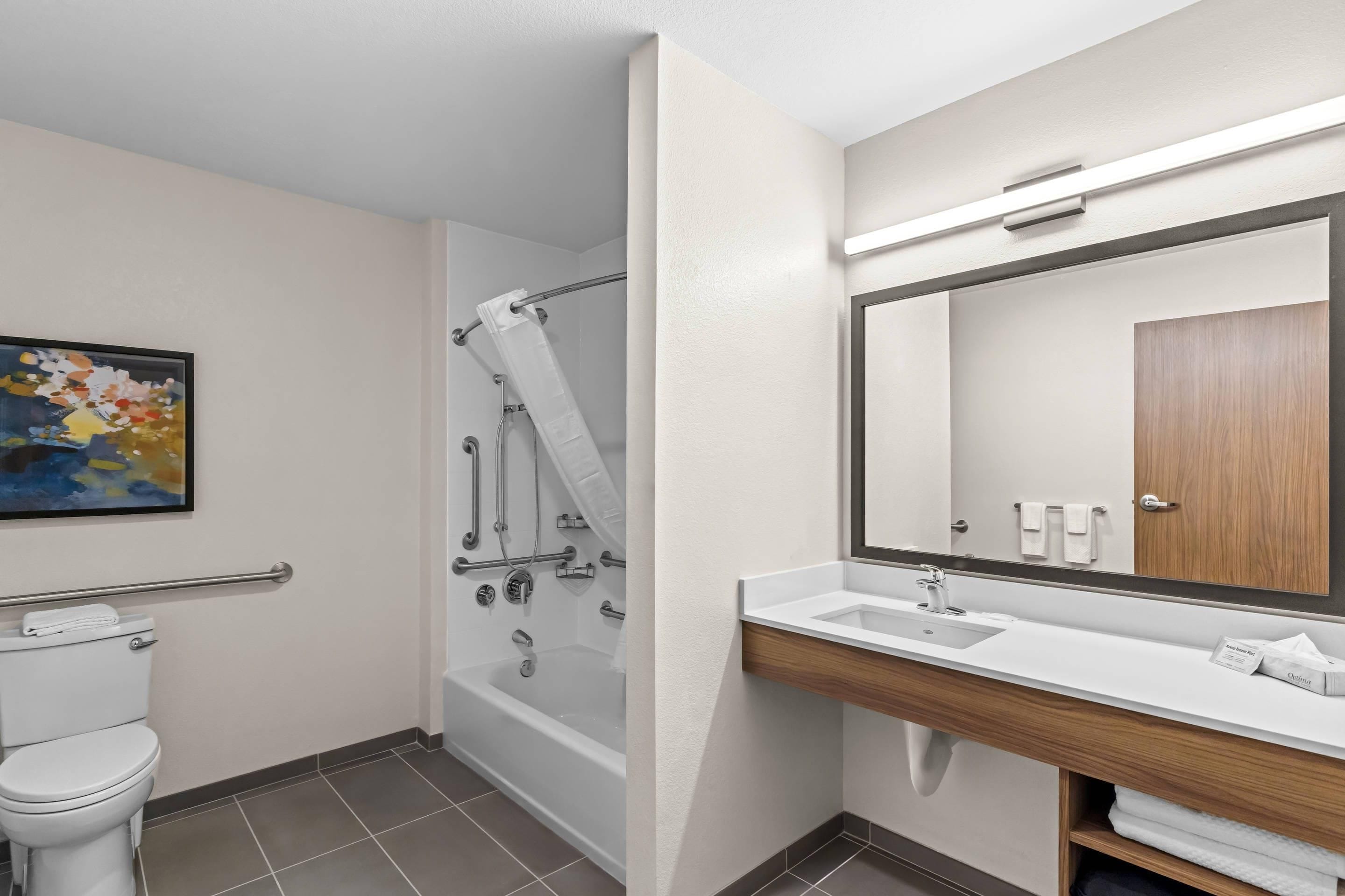 A modern bathroom with a toilet, shower, and sink.