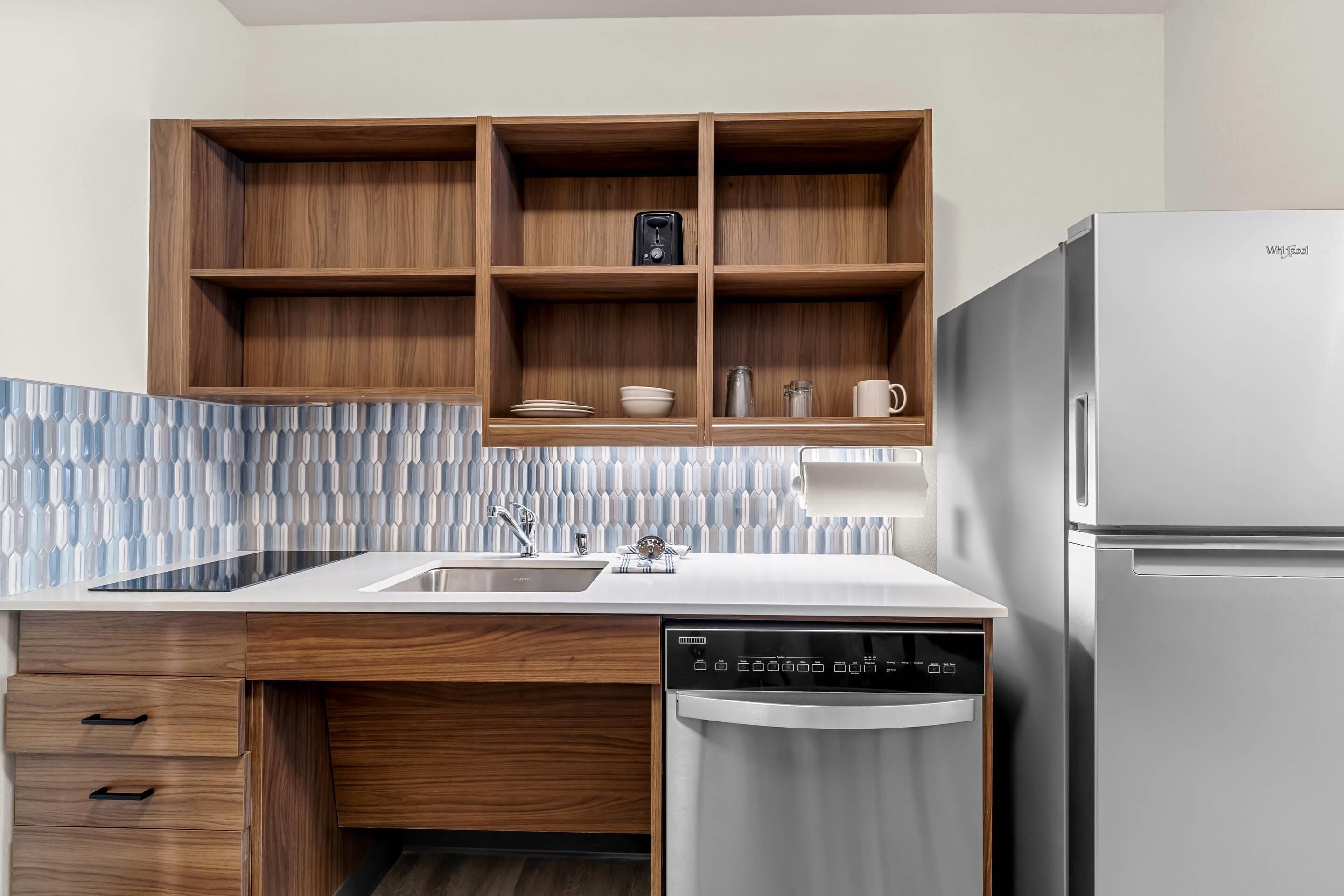 A modern kitchen with wooden cabinets, a dishwasher, and a refrigerator.
