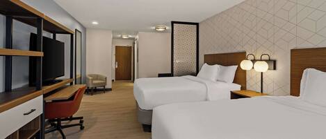 Une chambre d’hôtel avec deux lits, un bureau avec une chaise, une télévision et une lampe fixée au mur.