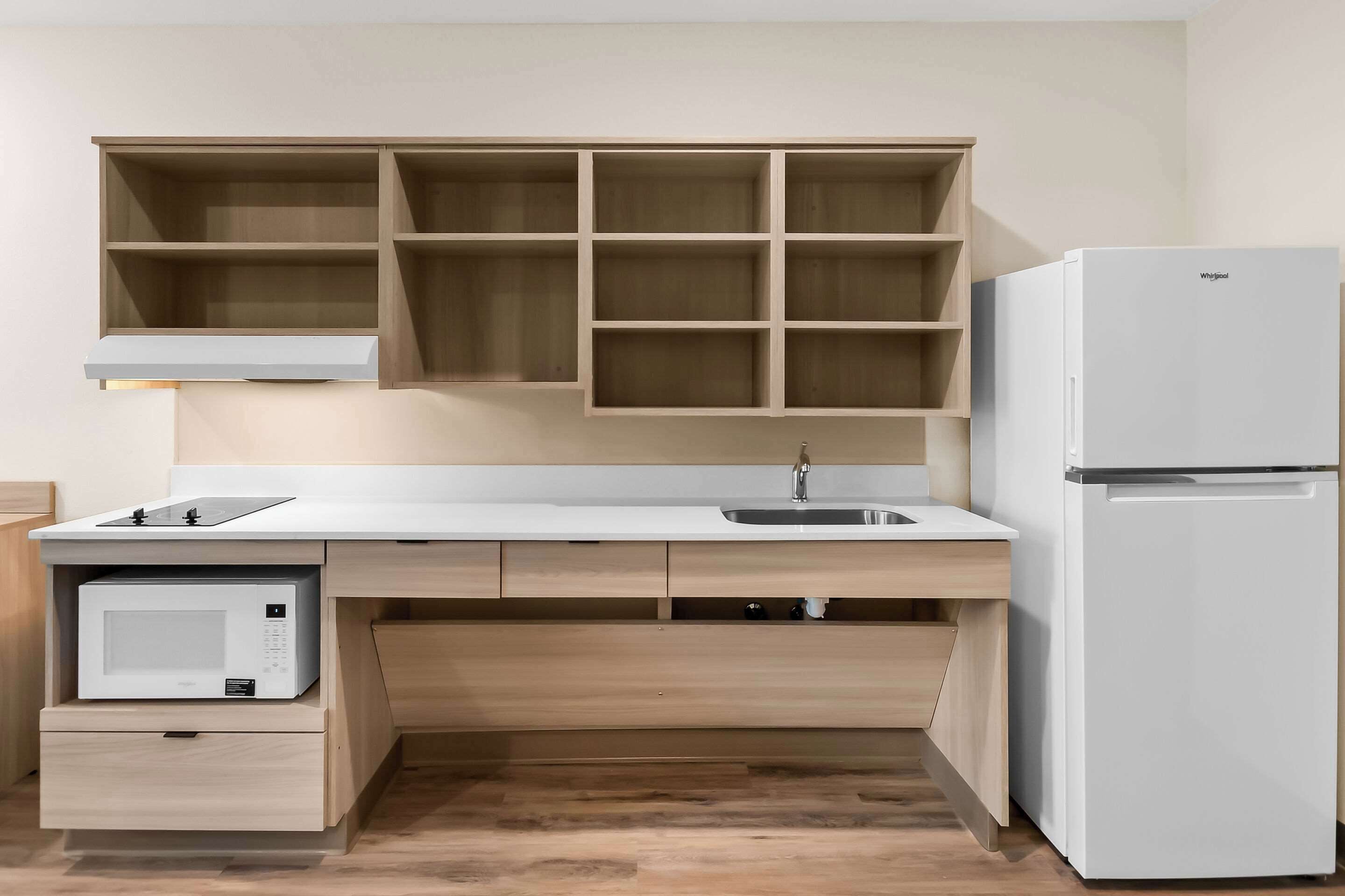 Eine kompakte Küche mit Mikrowelle, Kühlschrank und eingebauten Regalen.