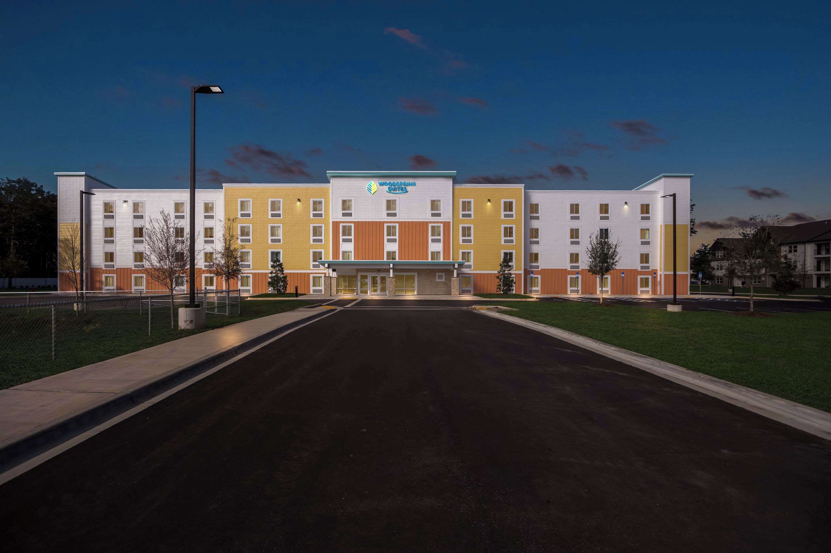 Un hôtel à plusieurs étages doté d’une entrée principale, d’un parking et d’une pelouse bien entretenue.