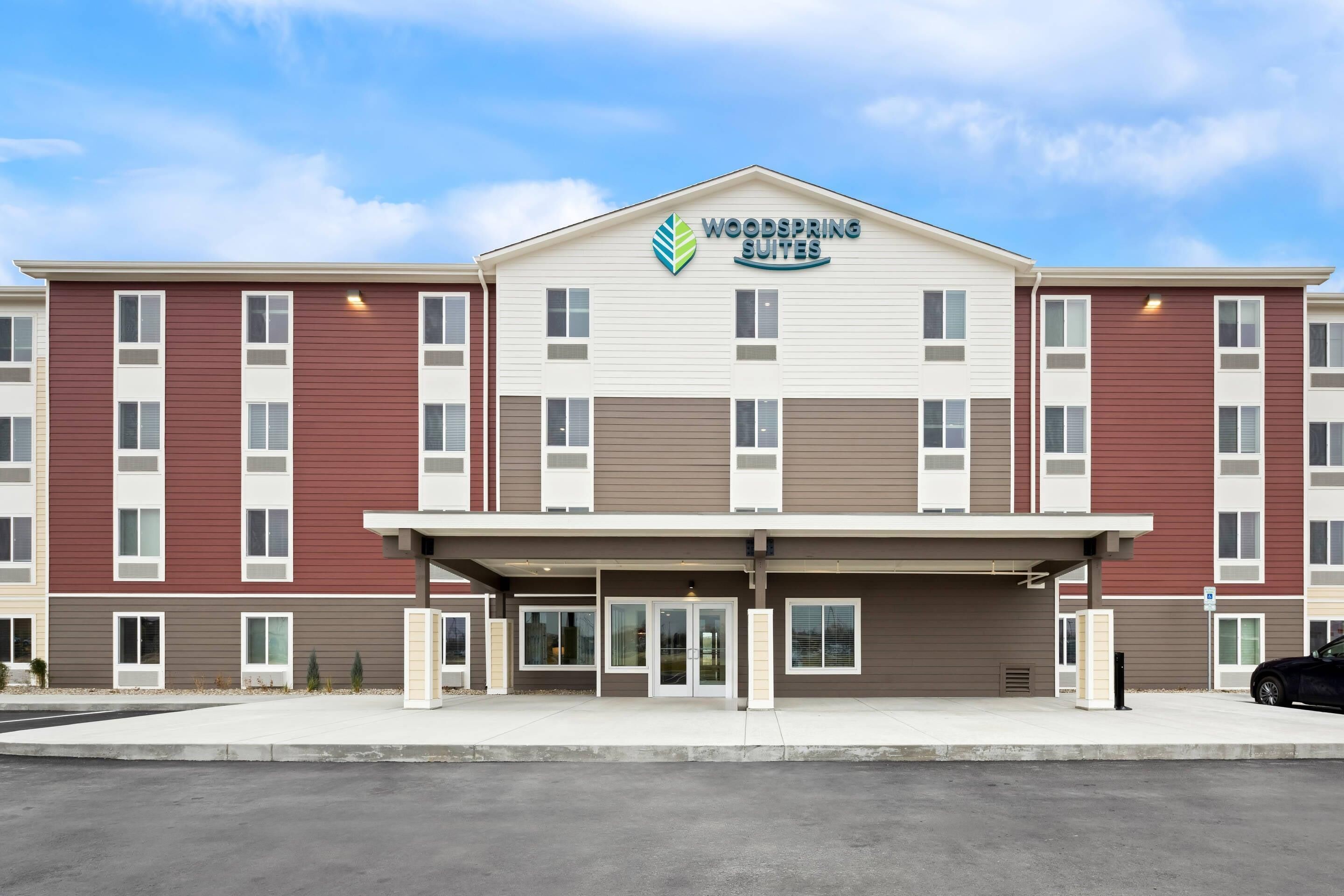 A multi-story hotel with a central entrance, large windows, and a clear sky.