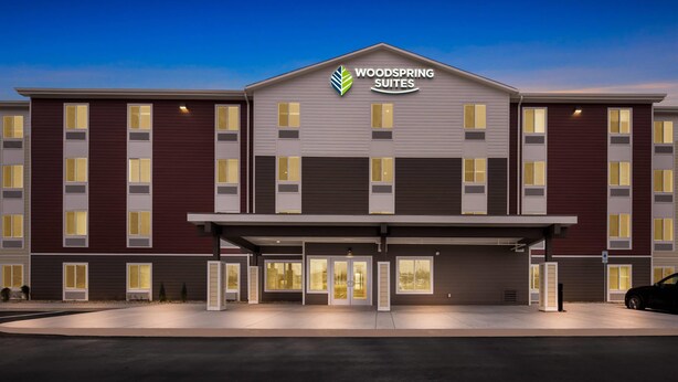 A modern hotel with a flat roof, a central entrance, and a parking area. - Woodspring Suites Billings (Billings)