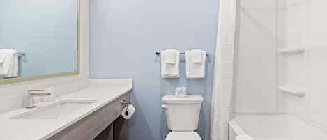 Un baño moderno con lavamanos, inodoro y bañera blancos.