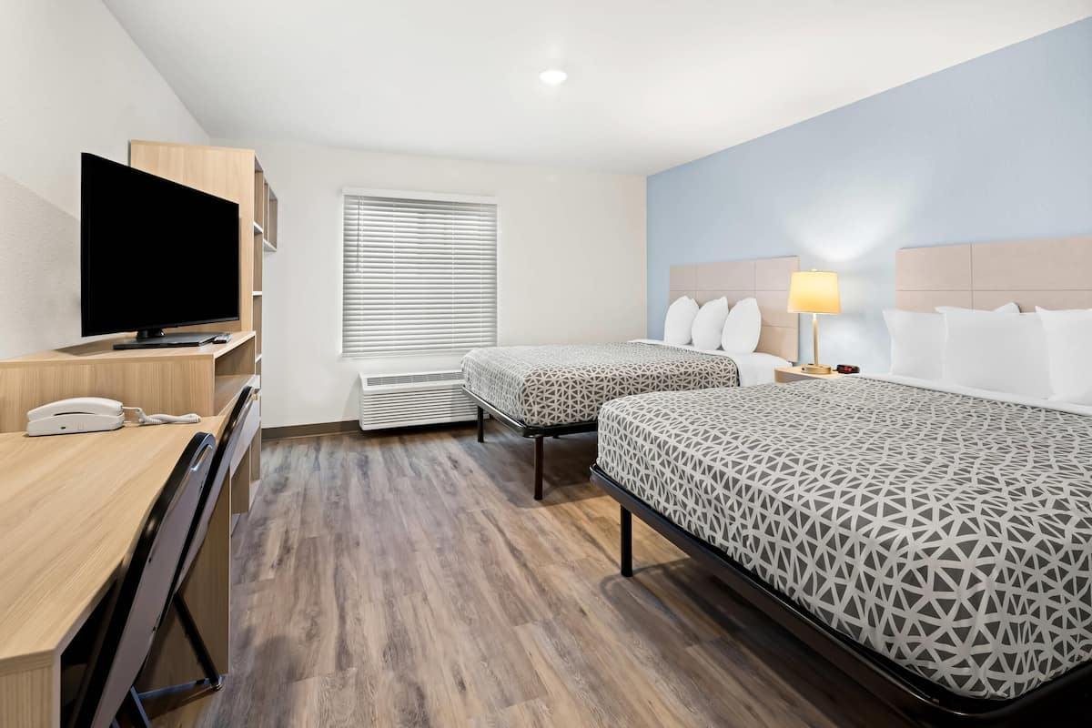 Une chambre d’hôtel avec deux lits, un bureau équipé d’une télévision, d’un téléphone et d’une lampe.