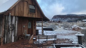 A rustic wooden building with a porch, a bench, and a chair. - 2 bedroom adobe home with AC, WiFi, great views, and new sauna and outdoor tub! (Cane Beds)