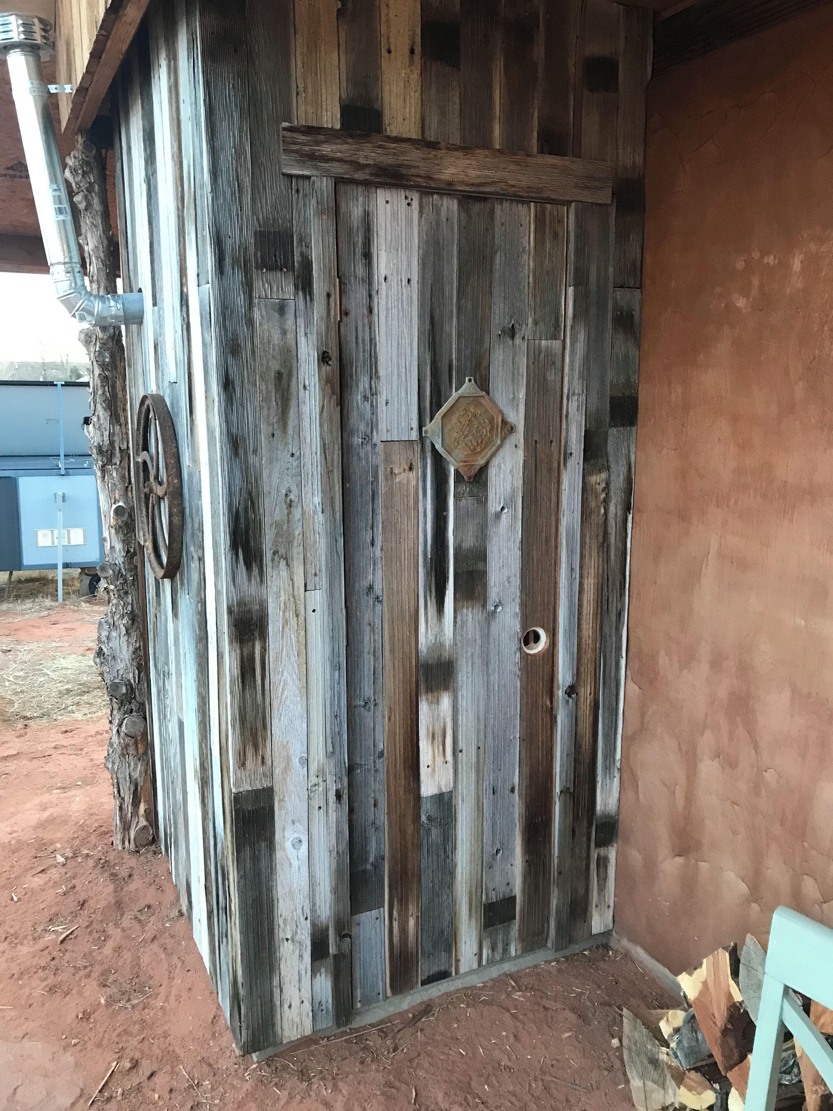 A rustic wooden door with a metal handle and a decorative plate.