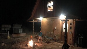 A rustic cabin with a stone fire pit, wooden furniture, and a single window. - 2 bedroom adobe home with AC, WiFi, great views, and new sauna and outdoor tub! (Cane Beds)